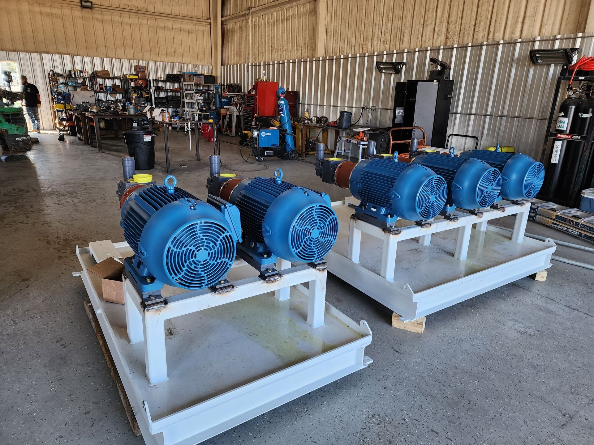 Industrial workshop with blue electric motors mounted on white platforms, surrounded by various tools and equipment.